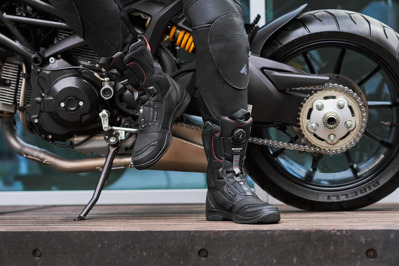 Motorcyclist wearing durable motorcycle riding boots next to a sleek motorcycle.